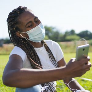 black-african-american-wearing-mask-watching-phone-in-park