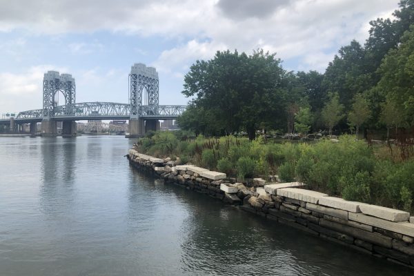 The Harlem river, looking toward the Bronx with a bridge and trees in view.
