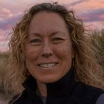 Headshot of Kim Milligan, with a sunset in the background