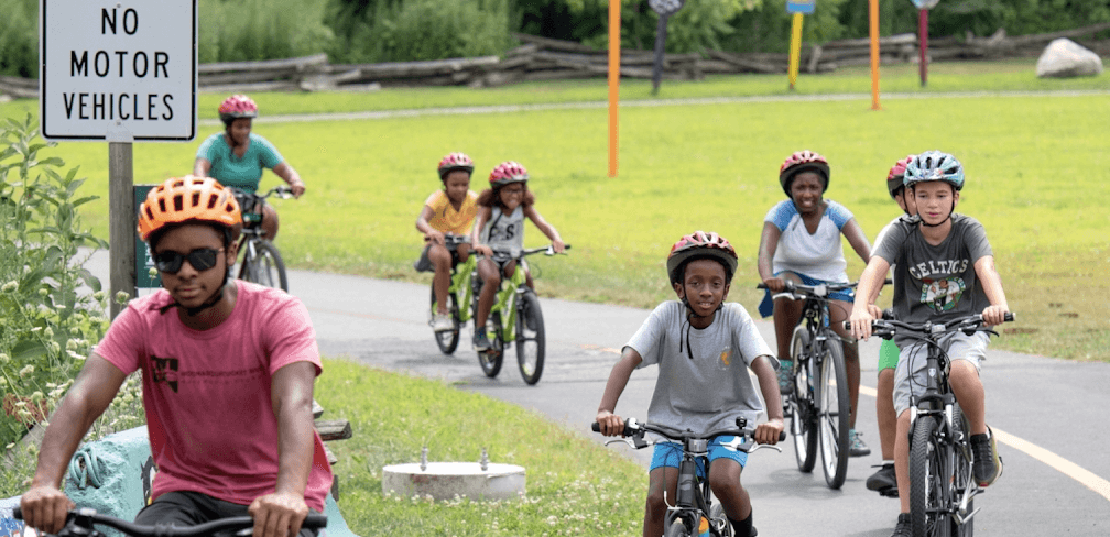 Kids and teens ride bikes along the Woonasquatucket Greenway.